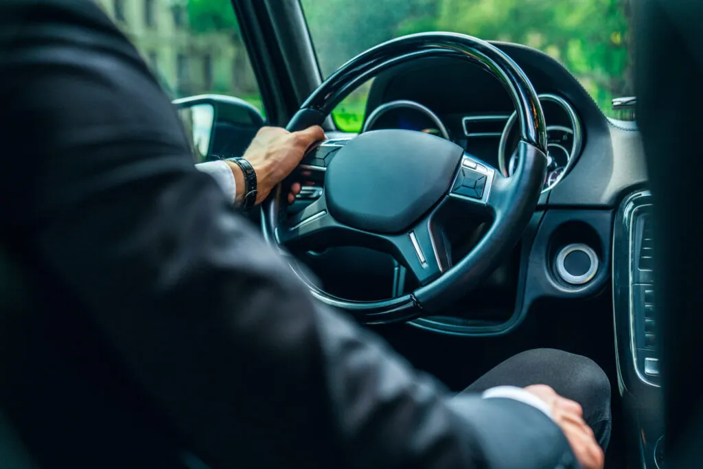 Chauffeur conduisant un minibus, main sur le volant vue depuis l’intérieur du véhicule
