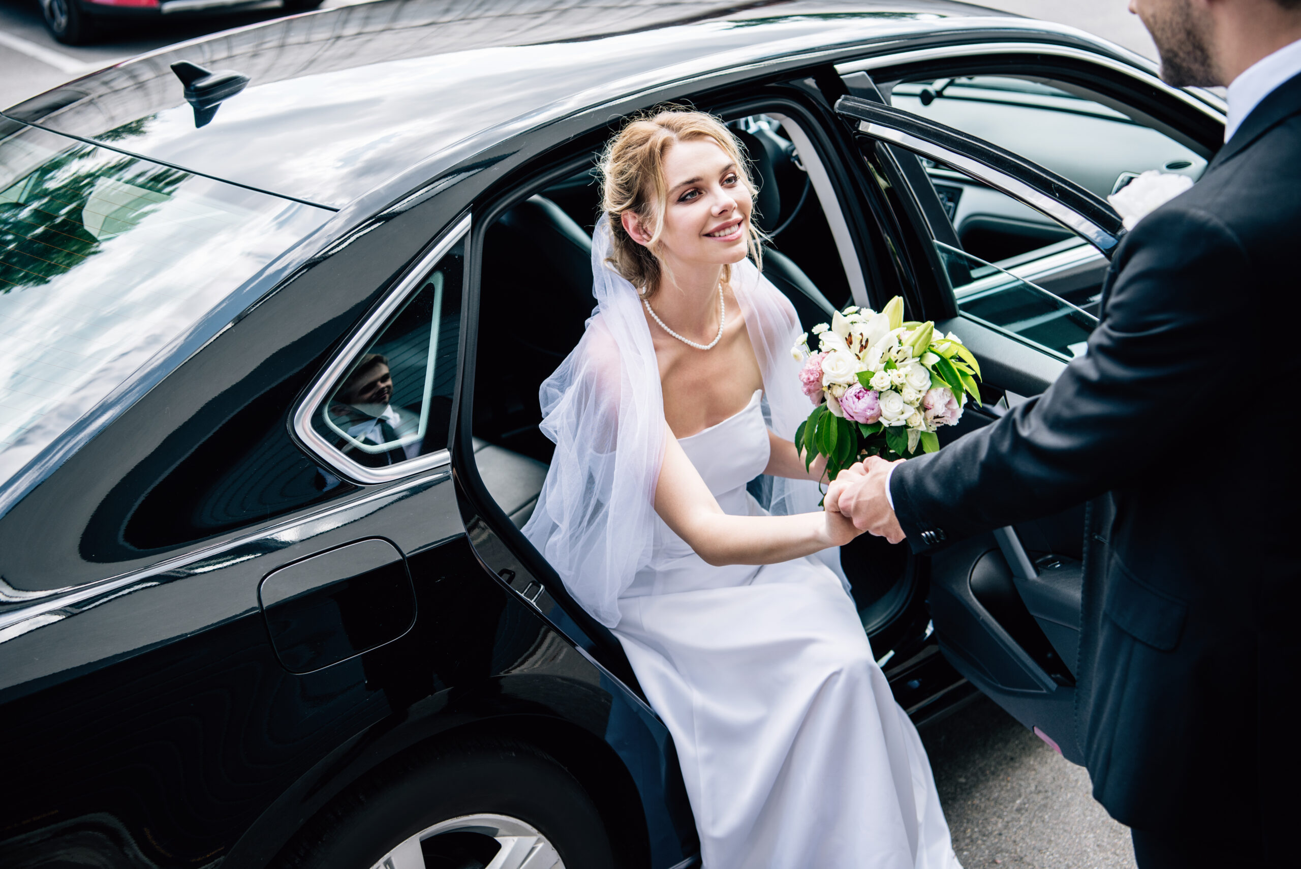 Mariée descendant d’une berline avec chauffeur lors d’un service de transport haut de gamme pour mariage